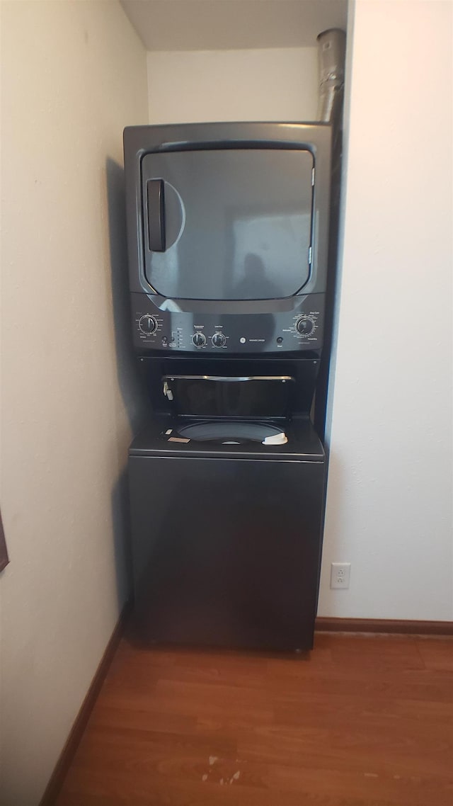 room details with hardwood / wood-style flooring and stacked washer and clothes dryer