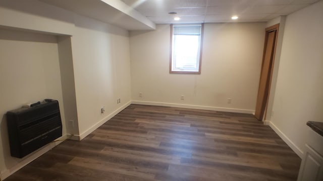 basement with heating unit, dark hardwood / wood-style flooring, and a drop ceiling