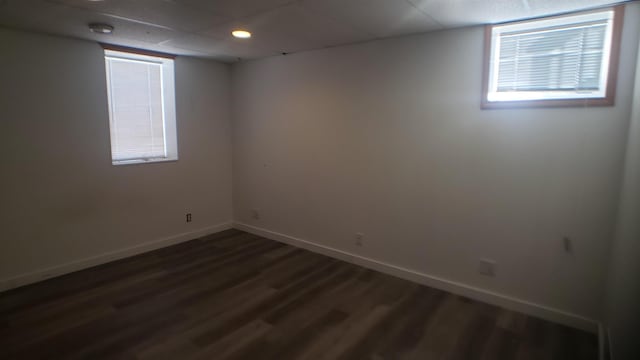 unfurnished room featuring dark wood-type flooring and a drop ceiling