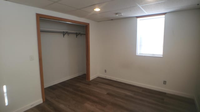 unfurnished bedroom featuring a paneled ceiling, dark hardwood / wood-style floors, and a closet