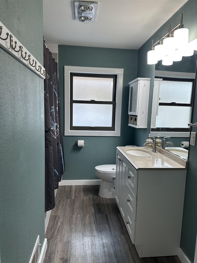 bathroom featuring vanity, wood-type flooring, toilet, and a textured ceiling