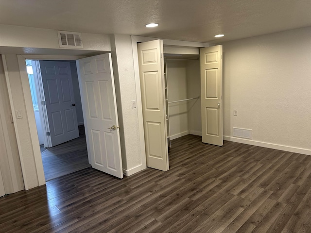 unfurnished bedroom featuring dark hardwood / wood-style flooring, a closet, and a textured ceiling