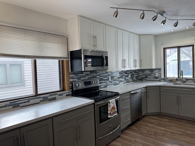 kitchen with dark wood-type flooring, sink, gray cabinetry, tasteful backsplash, and appliances with stainless steel finishes