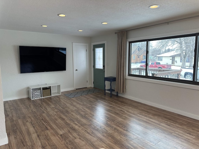 unfurnished living room featuring hardwood / wood-style flooring and a textured ceiling