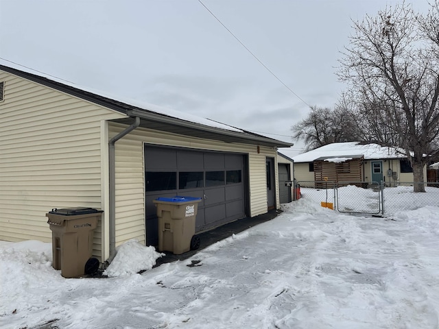 snow covered property featuring a garage and an outbuilding