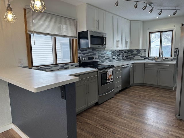 kitchen featuring sink, gray cabinets, stainless steel appliances, decorative light fixtures, and kitchen peninsula