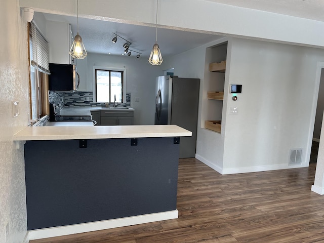 kitchen with stainless steel appliances, pendant lighting, a kitchen breakfast bar, and kitchen peninsula