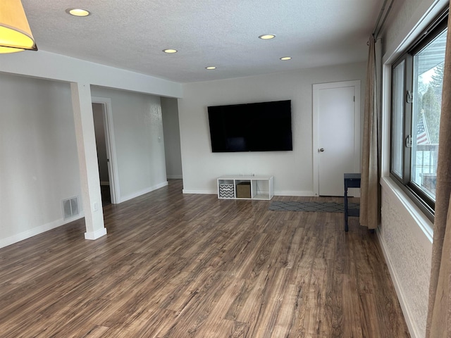 unfurnished living room with a textured ceiling and dark hardwood / wood-style flooring