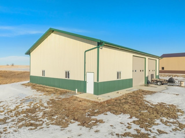 snow covered property with a garage and an outbuilding