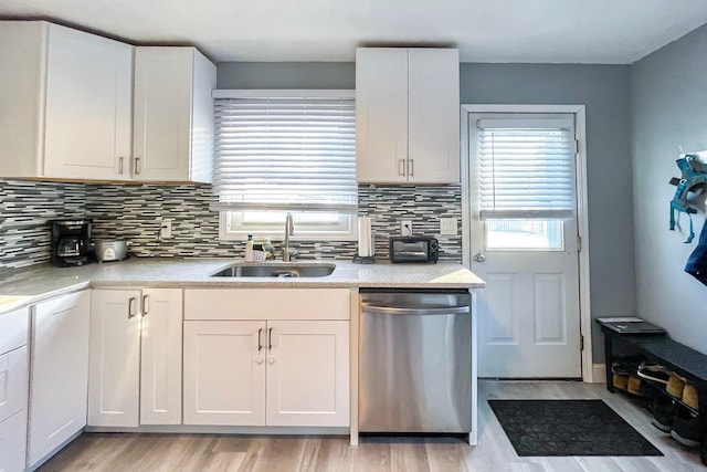 kitchen featuring tasteful backsplash, dishwasher, sink, and white cabinets