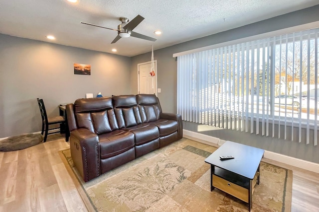 living room with ceiling fan, light hardwood / wood-style floors, and a textured ceiling