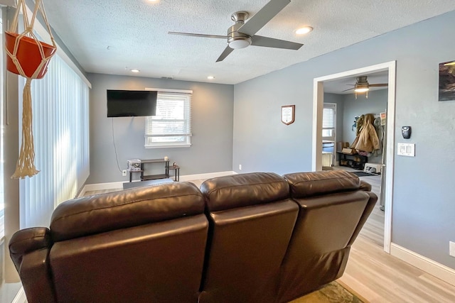 living room featuring ceiling fan, light hardwood / wood-style flooring, and a textured ceiling