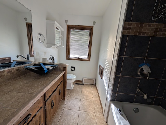 full bathroom featuring tile patterned flooring, vanity, tiled shower / bath, and toilet