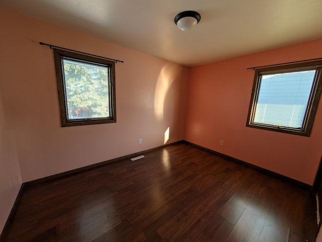 spare room featuring a healthy amount of sunlight and dark hardwood / wood-style floors