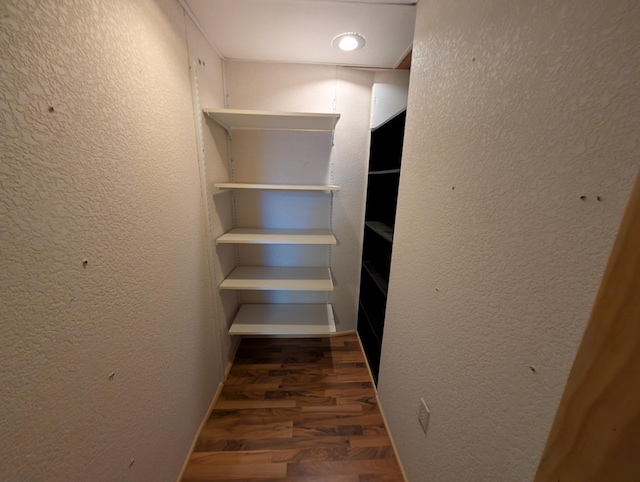 walk in closet with dark hardwood / wood-style floors