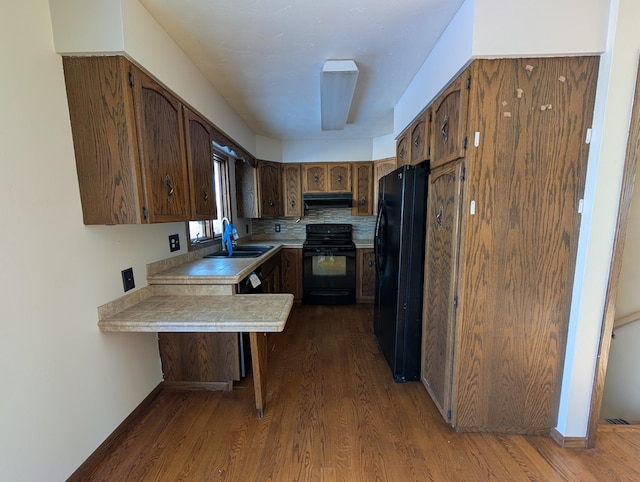 kitchen featuring sink, tasteful backsplash, dark hardwood / wood-style flooring, kitchen peninsula, and black appliances