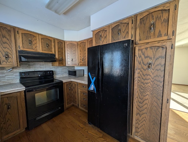 kitchen featuring backsplash, dark hardwood / wood-style floors, and black appliances