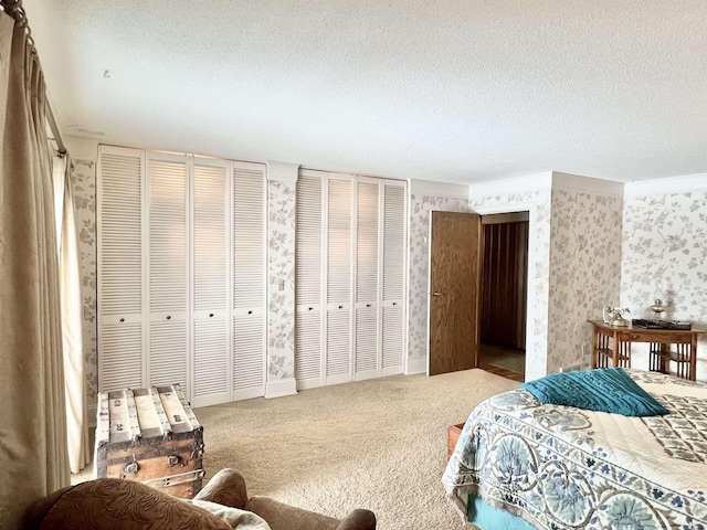 carpeted bedroom featuring a textured ceiling and two closets