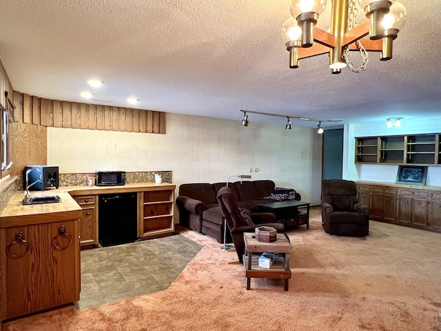 carpeted living room with sink, a textured ceiling, rail lighting, and a chandelier