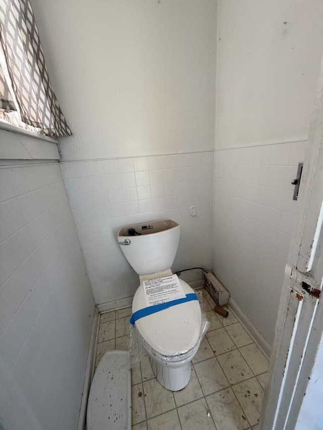 bathroom featuring tile walls, tile patterned floors, and toilet