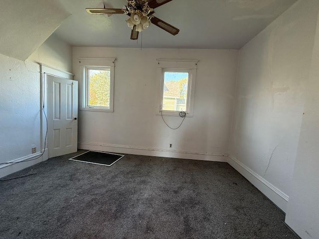 empty room featuring ceiling fan and dark carpet