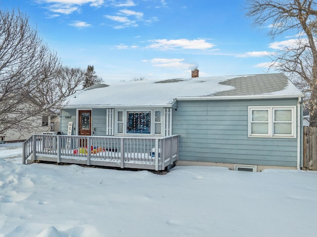 snow covered rear of property with a deck