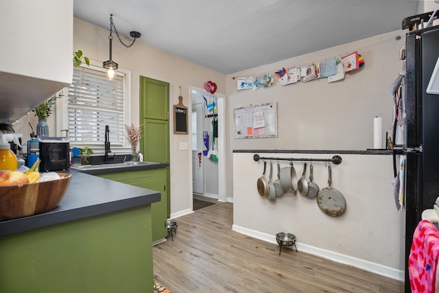 kitchen featuring sink, light wood-type flooring, and green cabinetry