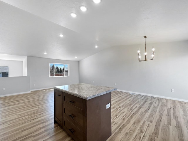 kitchen featuring pendant lighting, lofted ceiling, light hardwood / wood-style flooring, a notable chandelier, and a kitchen island