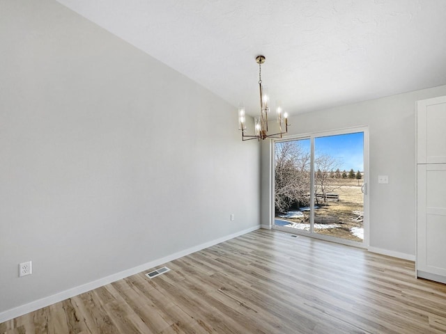 unfurnished dining area featuring light wood-type flooring and an inviting chandelier
