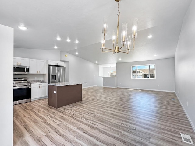 kitchen with pendant lighting, appliances with stainless steel finishes, an inviting chandelier, white cabinets, and a kitchen island