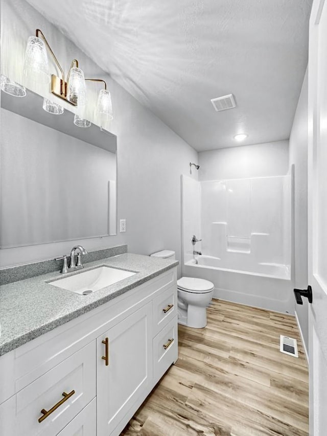 full bathroom with vanity, tub / shower combination, hardwood / wood-style floors, and toilet