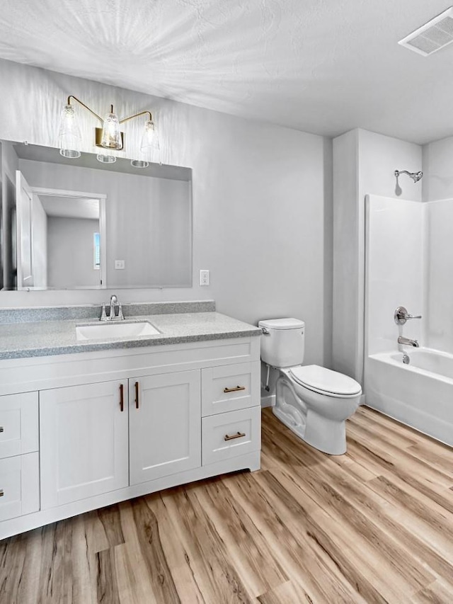 full bathroom featuring hardwood / wood-style flooring, shower / tub combination, vanity, and toilet