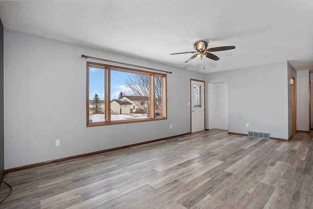 spare room with ceiling fan, a textured ceiling, and light wood-type flooring