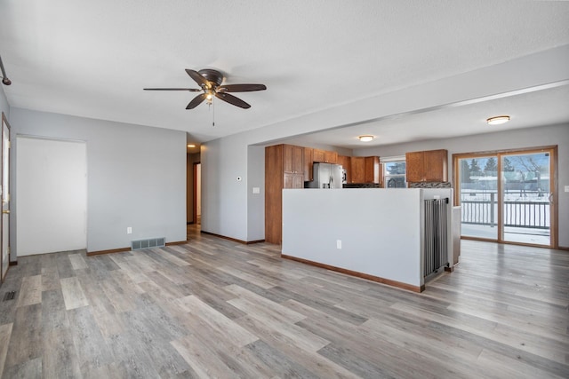 unfurnished living room featuring ceiling fan, a textured ceiling, and light hardwood / wood-style floors