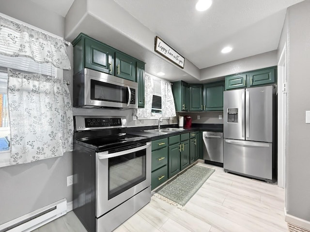 kitchen with appliances with stainless steel finishes, sink, green cabinets, and a baseboard heating unit