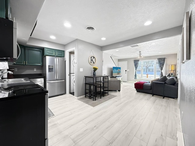 kitchen featuring light hardwood / wood-style flooring, stainless steel refrigerator with ice dispenser, sink, ceiling fan, and a textured ceiling