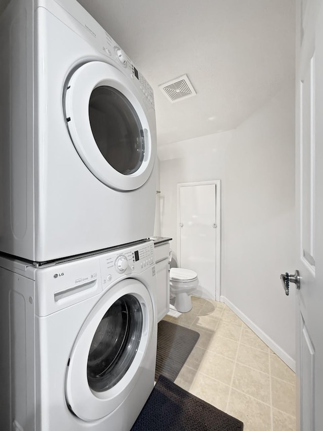 washroom featuring stacked washer and dryer and light tile patterned floors