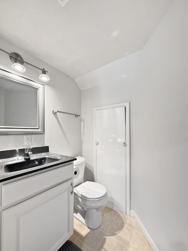 bathroom with lofted ceiling, tile patterned flooring, toilet, a textured ceiling, and vanity