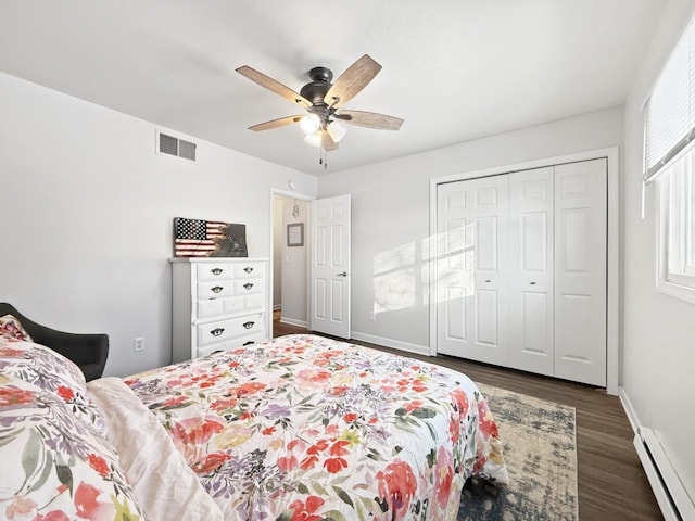 bedroom featuring baseboard heating, ceiling fan, dark hardwood / wood-style flooring, and a closet