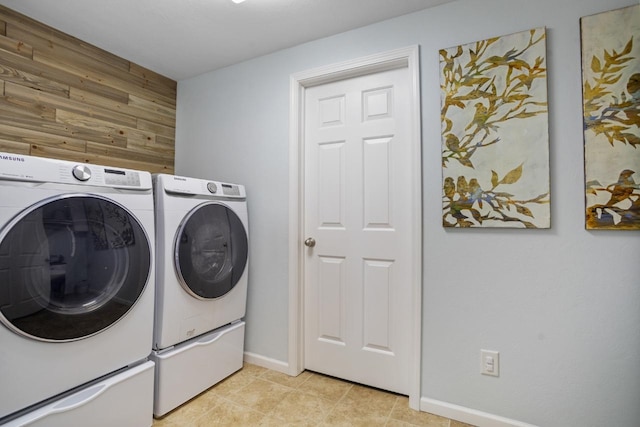 clothes washing area with baseboards, laundry area, wood walls, and washer and dryer