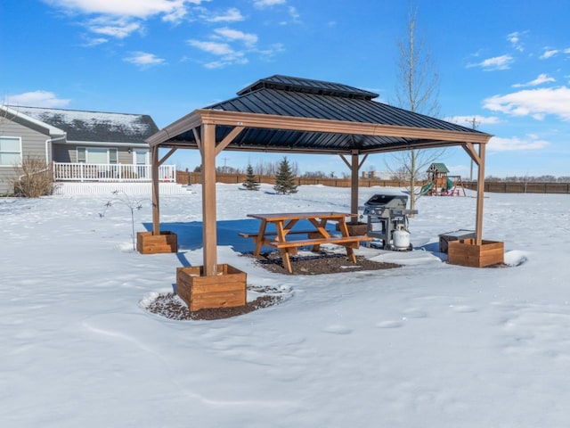 snow covered patio featuring grilling area, a playground, and a gazebo