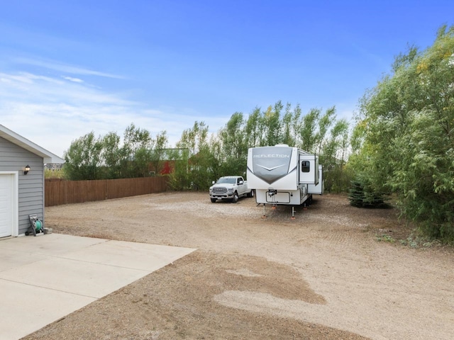 view of vehicle parking featuring driveway and fence