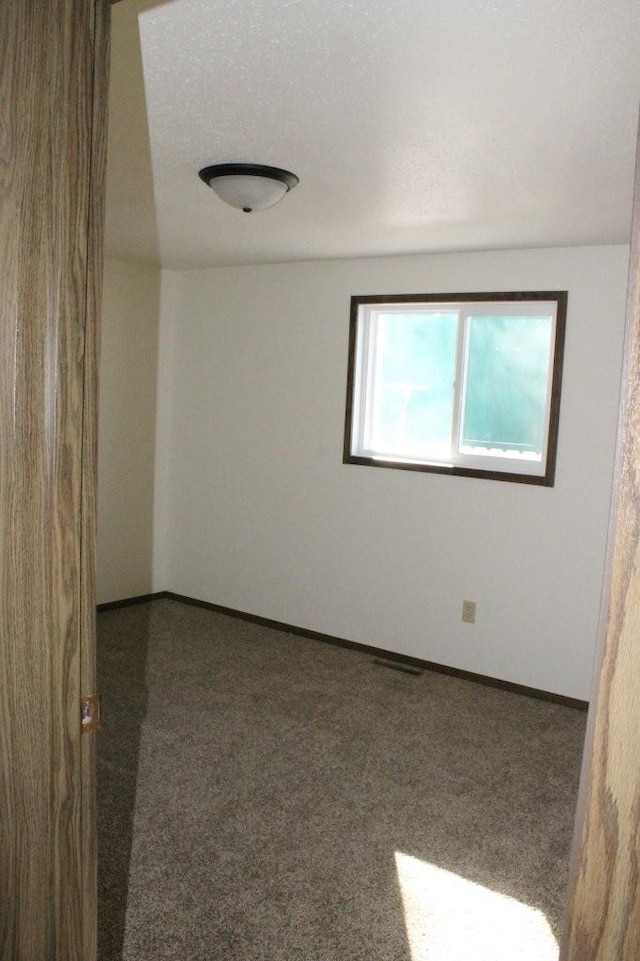 unfurnished room featuring dark colored carpet and baseboards