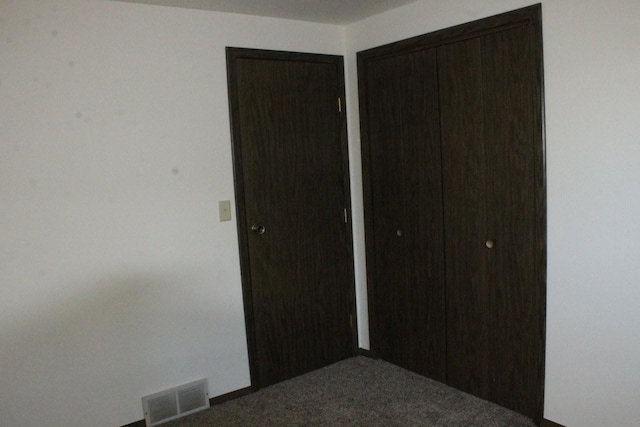 unfurnished bedroom with carpet floors, visible vents, and a closet