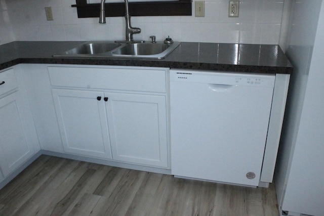 kitchen featuring dark countertops, light wood-style floors, white cabinets, a sink, and dishwasher