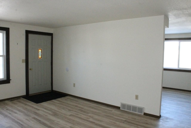 foyer entrance with wood finished floors, visible vents, and baseboards