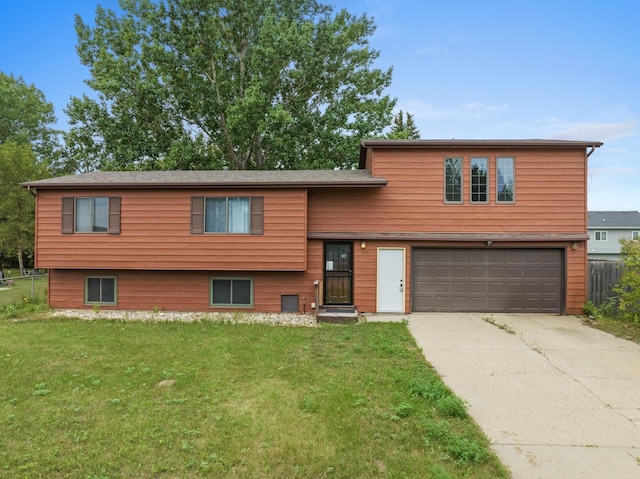 tri-level home with concrete driveway, fence, a front lawn, and an attached garage