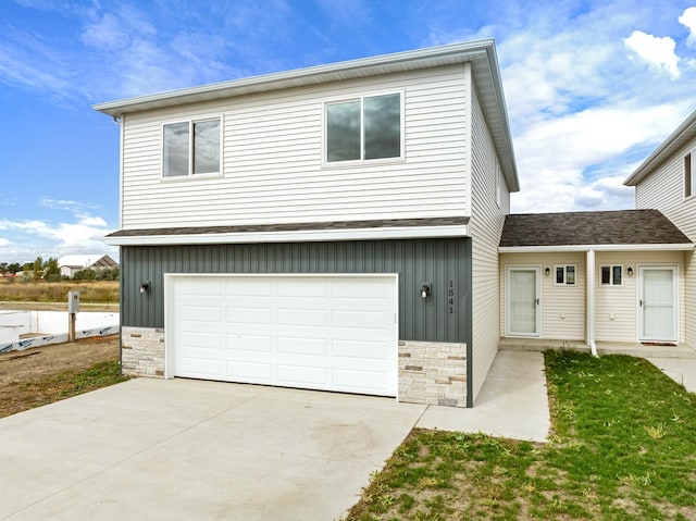 view of front of property with board and batten siding, stone siding, driveway, and an attached garage