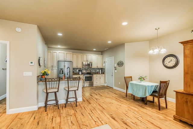 kitchen with a breakfast bar area, stainless steel appliances, a peninsula, decorative backsplash, and pendant lighting