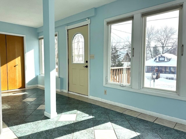 foyer featuring dark tile patterned flooring and baseboards